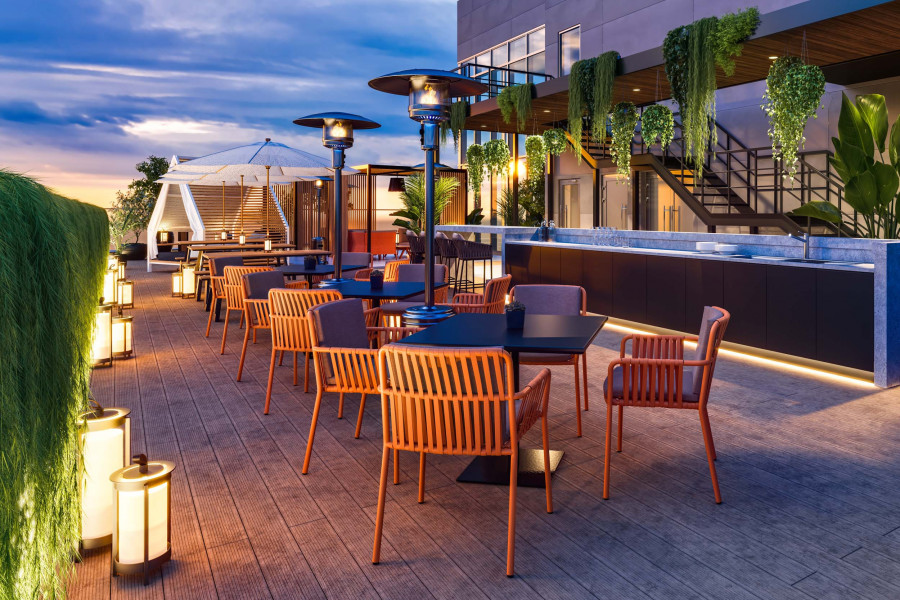 CGI of an outdoor rooftop terrace with timber decking, dining tables, heaters, and greenery at dusk.