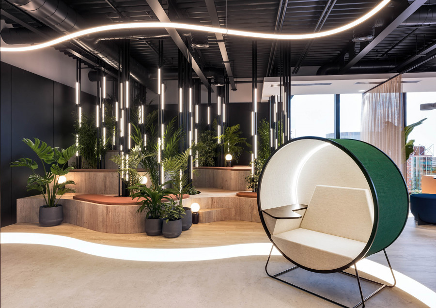 Visualization of a breakout area with suspended linear lights, stepped timber seating, and dense indoor planting.
