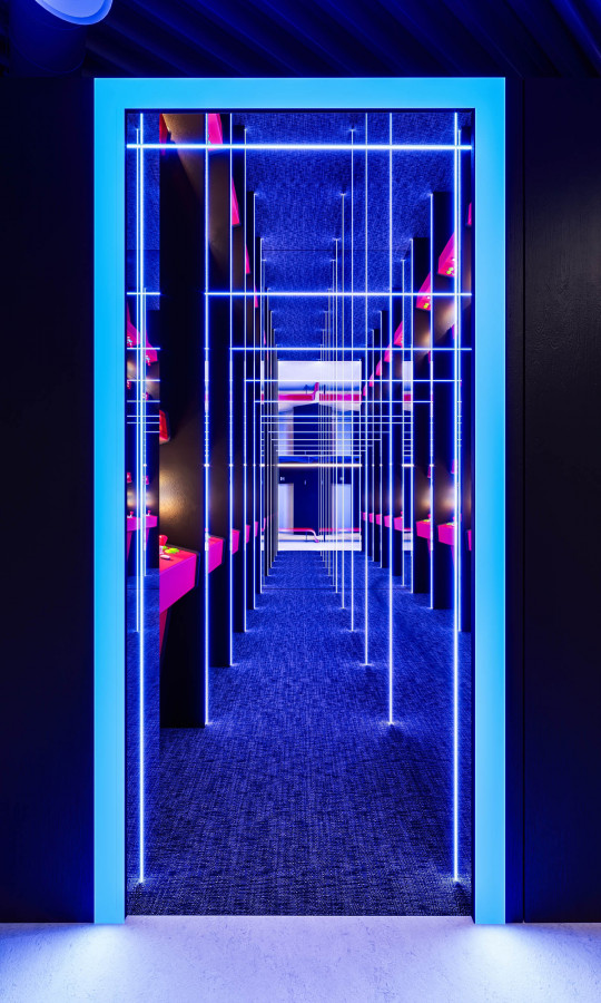 CGI of a corridor defined by vertical and horizontal neon blue lines creating a geometric immersive gaming-inspired space.
